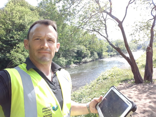 A photo of NRW staff inspecting a river bank for flood damage
