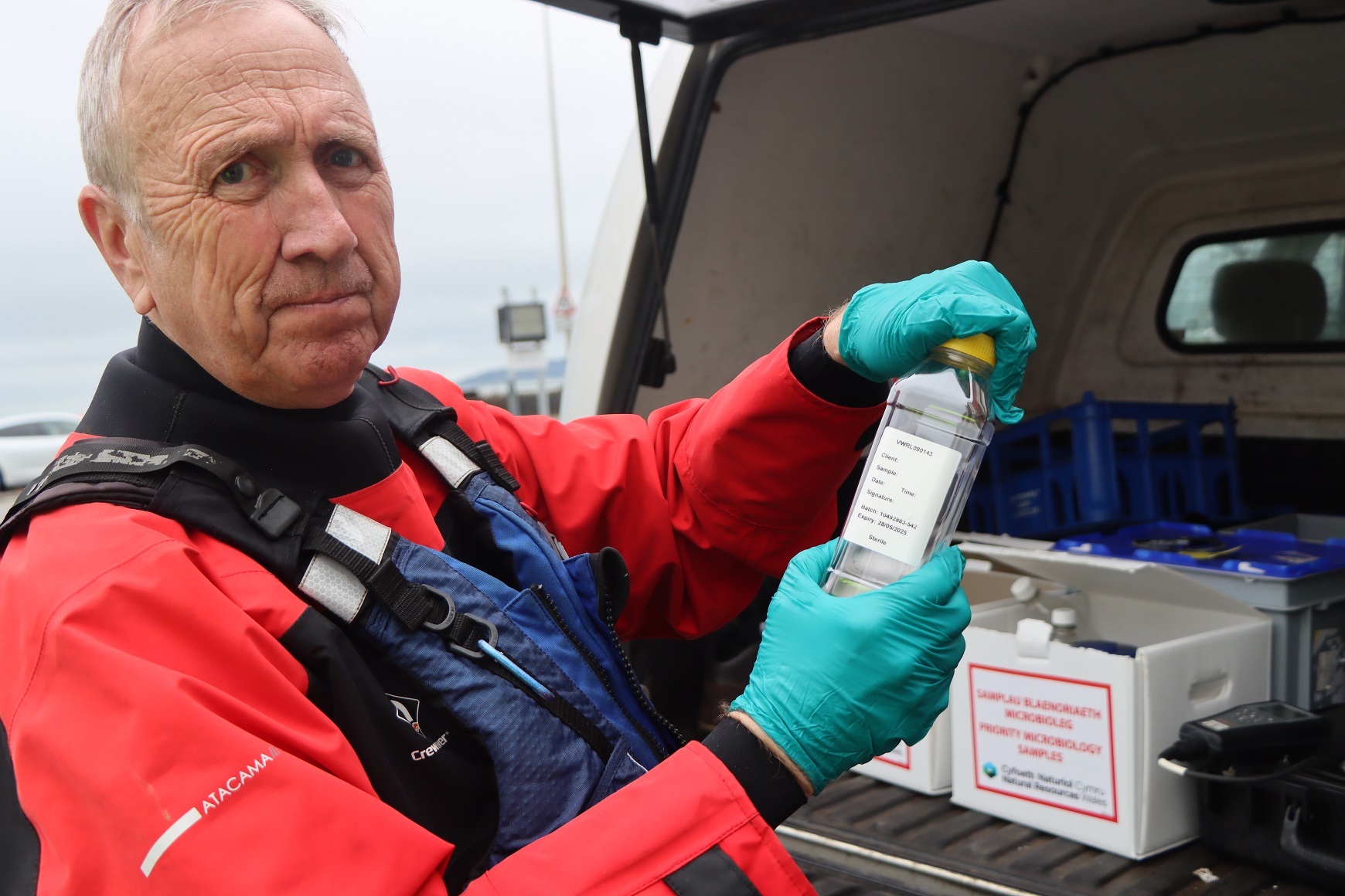 Sampler from NRW holding up a bottle containing bathing water samples