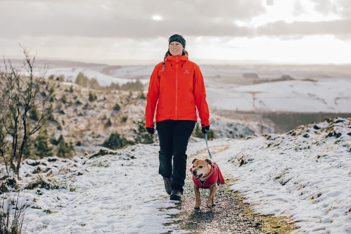 A woman and dog walking on a snowy hill